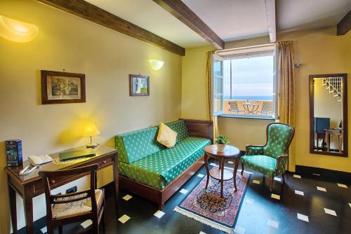 a living room with a green couch and a window at Palazzo Vescovile Hotel in Noli