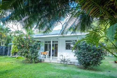 una casa blanca con una mesa y sillas en un patio en Vahine Ori Lodge, en Ataiti