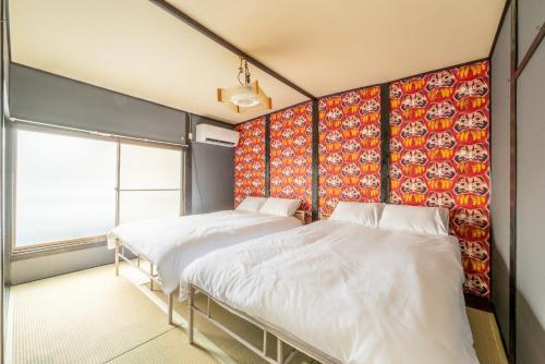 two beds in a room with a colorful wall at A comfortable house with easy access to Osaka city in Osaka