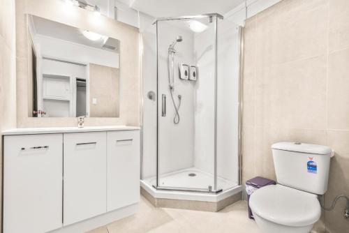 a white bathroom with a shower and a toilet at Albion Hotel in Auckland