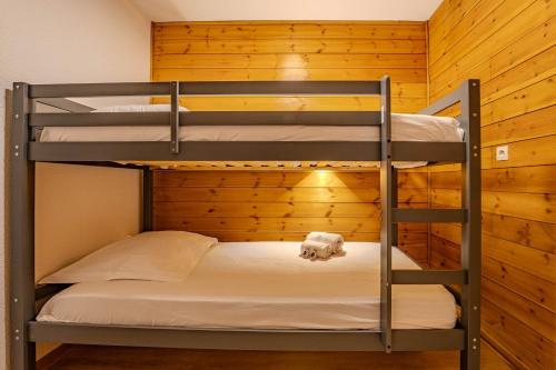 two bunk beds in a room with wooden walls at Ski in and out heart of Val Thorens - 1BR Sleeps 4 people in Val Thorens