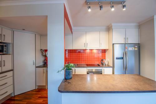 a kitchen with white cabinets and a stainless steel refrigerator at Spacious City Apartment - Walk to Casino, MCEC & MCG in Melbourne