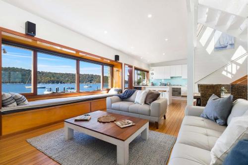 a living room with two couches and a table at Waterfront Scotland Island Holiday Home - Family & Pet Friendly - 3 Bedrooms - Wifi - Netflix - Private Jetty in Scotland Island