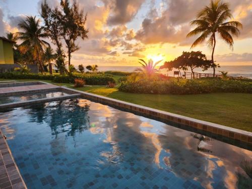 a swimming pool with a sunset in the background at Kauai Beach Residence 403 in Tamandaré