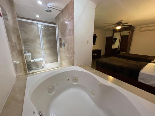 y baño con bañera grande y cama. en Hotel Rincon Real Suites, en Durango
