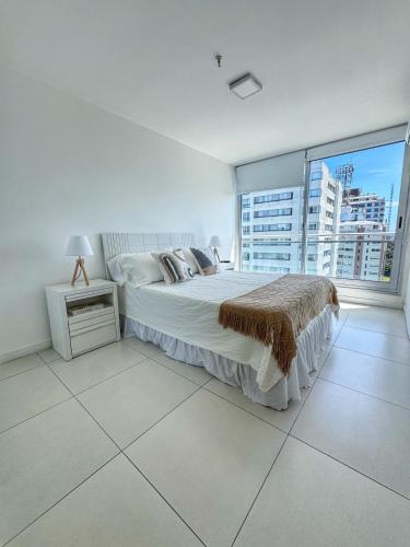 une chambre blanche avec un lit et une grande fenêtre dans l'établissement Torre Bellagio - Piso 17 - Full Amenities - 4 Pax - Piscina Climatizada, à Punta del Este