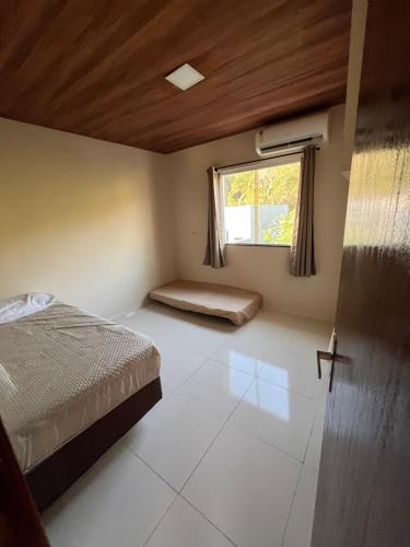 un dormitorio con una cama y una ventana en Vivenda da Alegria, en Vera Cruz de Itaparica