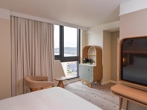 a hotel room with a bed and a large window at voco Gosford by IHG in Gosford