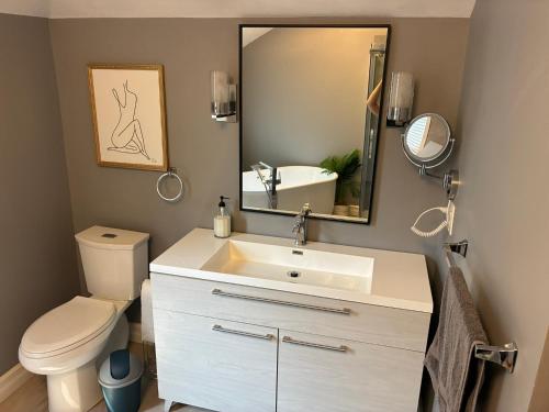 une salle de bain avec un lavabo, des toilettes et un miroir dans l'établissement 4 Bedrrom Downtown Gem, Modern, Comfort, Fireplace, Huge Backyard, Steps to Lake and Broadwalk, à Temiskaming Shores