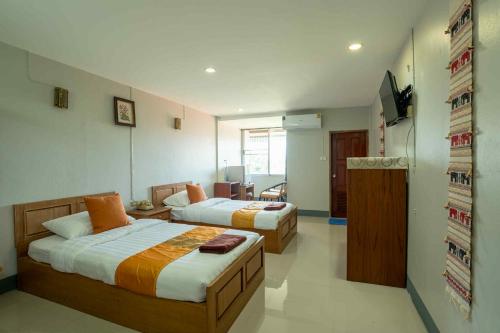 a hotel room with two beds and a television at โรงแรมเชียงดาวอินน์ Chiangdaoinnhotel in Chiang Dao