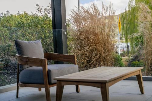 une chaise en bois, un banc et une table dans l'établissement Lakefront Luxury 2 Bedroom Apartment, à Wanaka