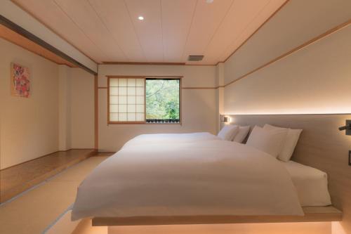 una camera da letto con un grande letto bianco e una finestra di Komakusa Hotel a Matsumoto