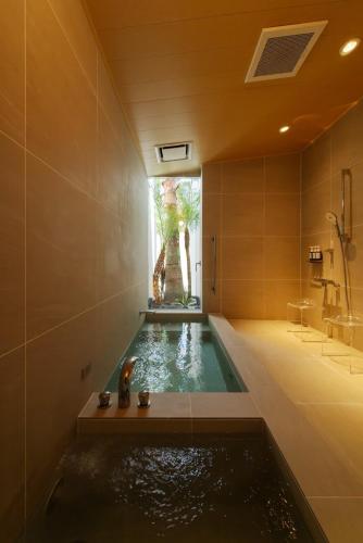 a bathroom with a bath tub with a sink at Asnova Resort FLORES ATAMI in Atami