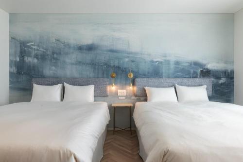 Asnova Resort FLORES ATAMI في أتامي: سريرين يجلسان بجانب بعضهما البعض في غرفة