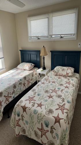 a bedroom with two beds and a table with a lamp at Holgate Ocean Front Duplex 2Nd Fl 14018 in Holgate