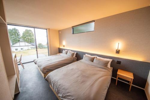 two beds in a hotel room with a window at Doggo伊豆　愛犬と過ごす最高の時間の為に造られた貸切宿。温泉、プライベートドッグランで最高の一時を。 in Ito