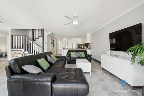 a living room with a leather couch and a tv at Park Beach Surfside Escape in Coffs Harbour