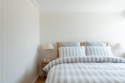 un lit avec des draps rayés bleus et blancs et deux lampes dans l'établissement Magpie Sands - Ocean Views & Seaside Luxury - Steps to beach, à Aldinga Beach