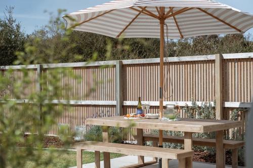 une table de pique-nique avec un parasol sur une clôture dans l'établissement Magpie Sands - Ocean Views & Seaside Luxury - Steps to beach, à Aldinga Beach