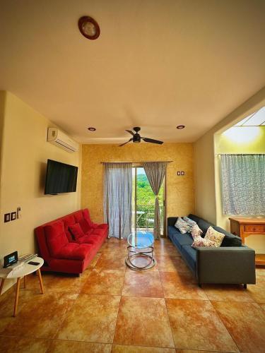 a living room with two couches and a red couch at Penthouse en Huatulco con alberca, balcón, 5 min playa in Santa Cruz Huatulco