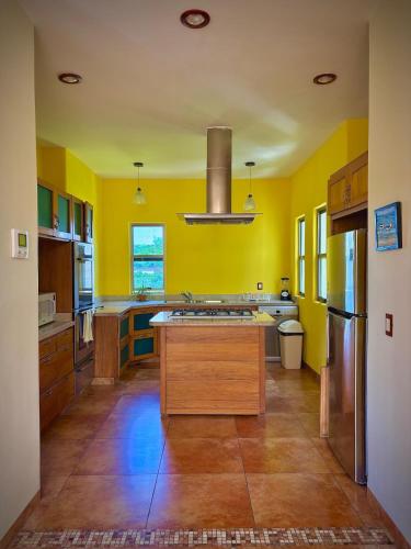 a large kitchen with yellow walls and wooden floors at Penthouse en Huatulco con alberca, balcón, 5 min playa in Santa Cruz Huatulco