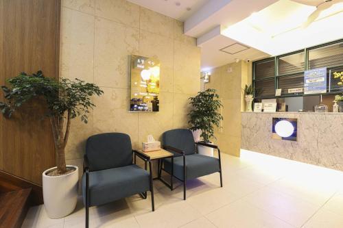 a waiting room with two chairs and a table and a tree at Gijang Ryan Hotel in Busan