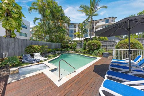 a swimming pool with chairs and an umbrella at Ocean Vista Retreat - Walk to Mooloolaba & Alex in Mooloolaba