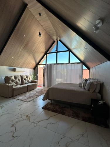 een slaapkamer met een bed en een bank op zolder bij Chalé do chamego in Alto Paraíso de Goiás