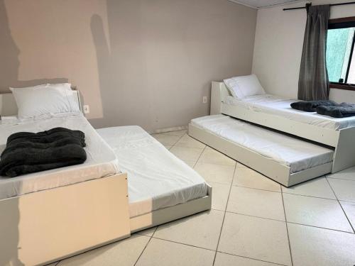 two beds in a room with white walls at Sweet Laguna Luxury House in Iguaba Grande