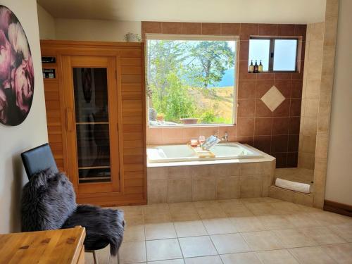 a bathroom with a tub and a dog looking out the window at Rose Ridge Retreat in Upper Moutere