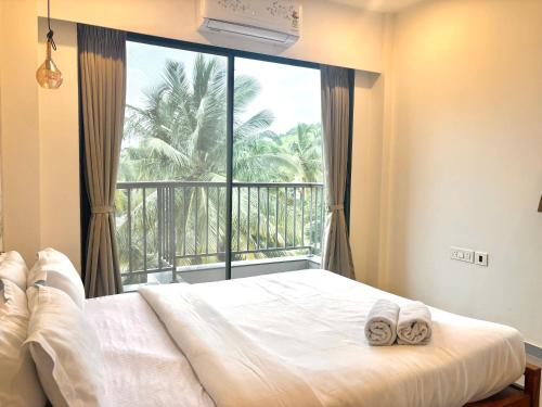 a bedroom with a bed and a large window at Relaxing 2BHK with Mangrove View - Family-Friendly, Pool - Candolim Beach in Candolim