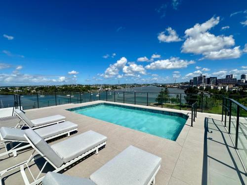 a swimming pool with chairs and a view of the water at New City Condo with Brisbane River View & Parking in Brisbane