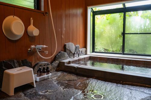a bathroom with a bath tub and a window at 山荘 紗羅樹 Syaranoki in Yufuin