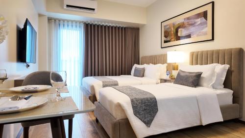 una habitación de hotel con dos camas y una mesa en Savea Bay City Manila, en Manila