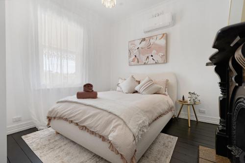 a white bedroom with a bed with a teddy bear on it at Courthouse - Family Retreat Near Bendigo CBD in Bendigo
