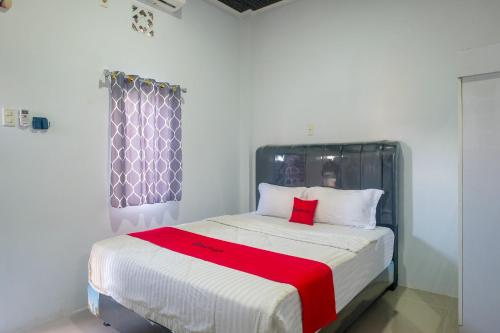 a bedroom with a bed with a red blanket on it at RedDoorz at MG House Siantar Timur in Pematangsiantar
