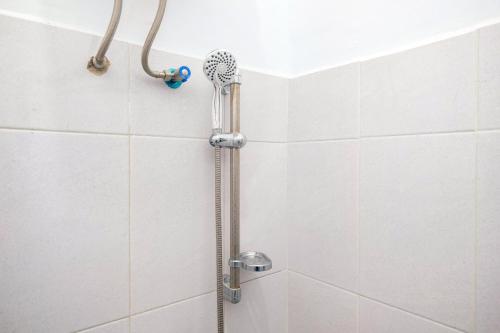a shower with a shower head in a bathroom at RedDoorz at MG House Siantar Timur in Pematangsiantar