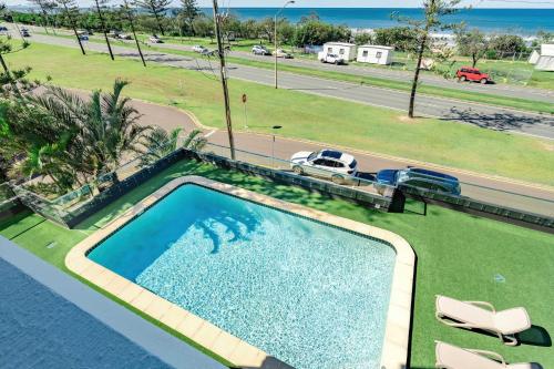 an overhead view of a swimming pool with chairs and a road at Shara Seaside Oasis - Alex Beach 3BD Apartment in Alexandra Headland