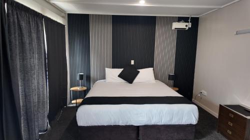a bedroom with a bed with black and white sheets at Bay Lodge Motel in Tauranga