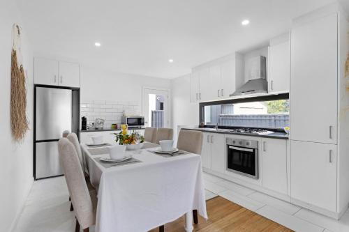 Una cocina blanca con una mesa y sillas blancas. en California 'Luxe Boho' with Pool, en Echuca