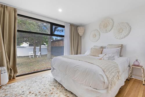 a bedroom with a white bed and a large window at California 'Luxe Boho' with Pool in Echuca