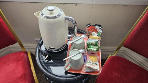 a tea kettle sitting on a table between two chairs at Winston House Guesthouse in Bridlington