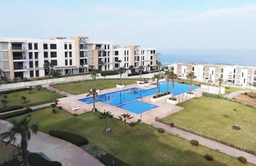 un complexe d'appartements avec une grande piscine et des bâtiments dans l'établissement Cozy 2 Bedroom Prestigia - close to Plage des Nations, à Sidi Bouqnadel