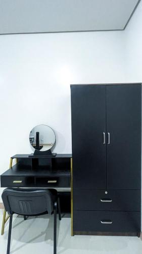 ein schwarzer Schreibtisch mit Spiegel und einem schwarzen Schrank in der Unterkunft SM 3 Cozy Corner Retreat in Sampong