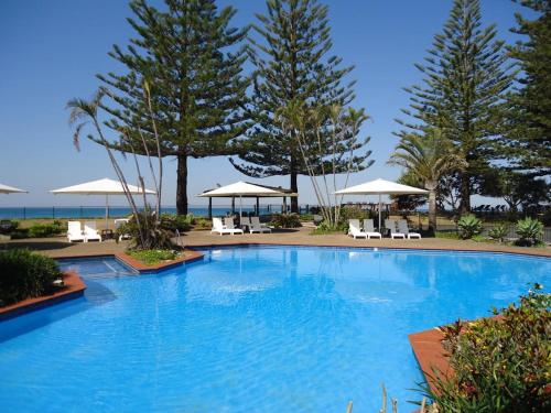 a large swimming pool with chairs and umbrellas at Hibiscus Villa - Beachfront, 2 pools, Tennis, Restaurant in Kororo Basin