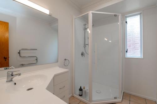 a white bathroom with a shower and a sink at Ohope Ocean Breeze Escape in Ohope Beach