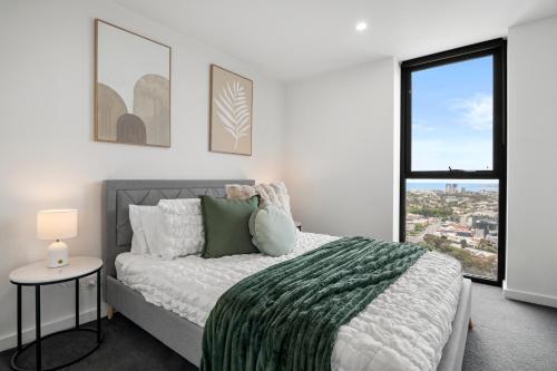 a white bedroom with a bed and a window at Luxe High-Floor Retreat- Epic Views-Steps to Crown in Melbourne
