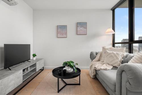 a living room with a couch and a tv at Luxe High-Floor Retreat- Epic Views-Steps to Crown in Melbourne