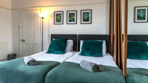 ダービーにある6 BDR House By Eason Stays Short Lets & Serviced Accommodation Derby With Free Parkingの緑の枕と鏡が付いたベッドが2つある寝室