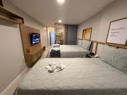 a hotel room with two beds and a flat screen tv at 509 Flat praia piscina barzinho Intermares in Cabedelo